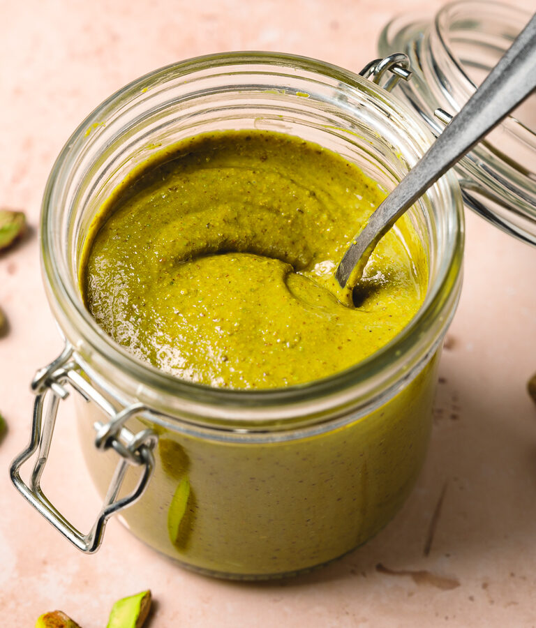 homemade pistachio butter in glass jar with a spoon.